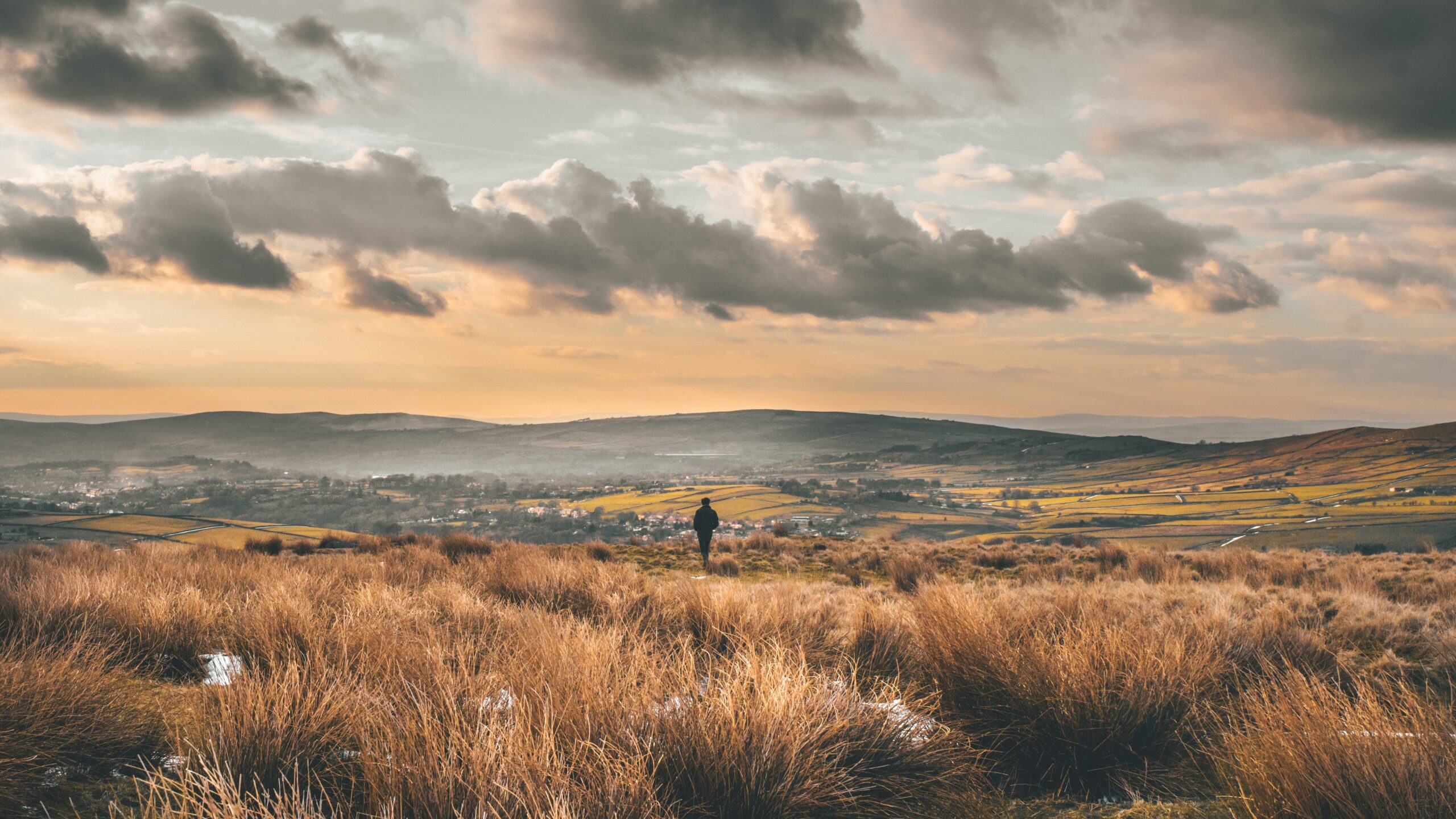 Distant figure stands in frosty scene looking over moorland