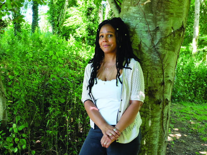 Photograph of Louisa Adjoa Parker standing up and leaning against a tree