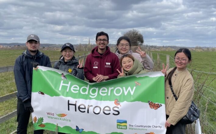 People holding a banner in the countryside with 'Hedgerow Heroes' written on it