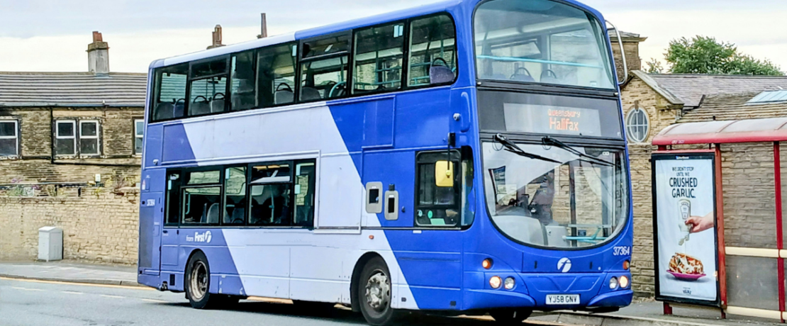 A blue bus near a bus stop in a suburban area