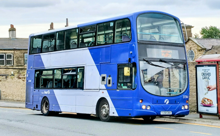 A blue bus near a bus stop in a suburban area