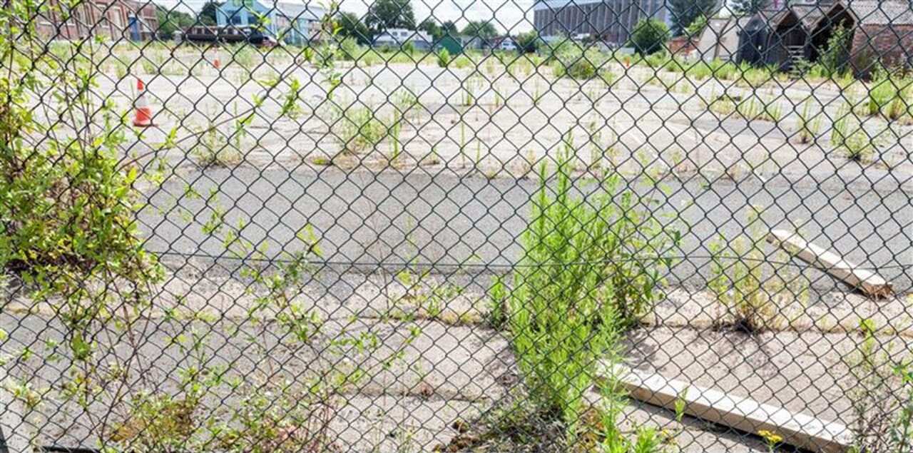 Unused brownfield site seen through wire fencing