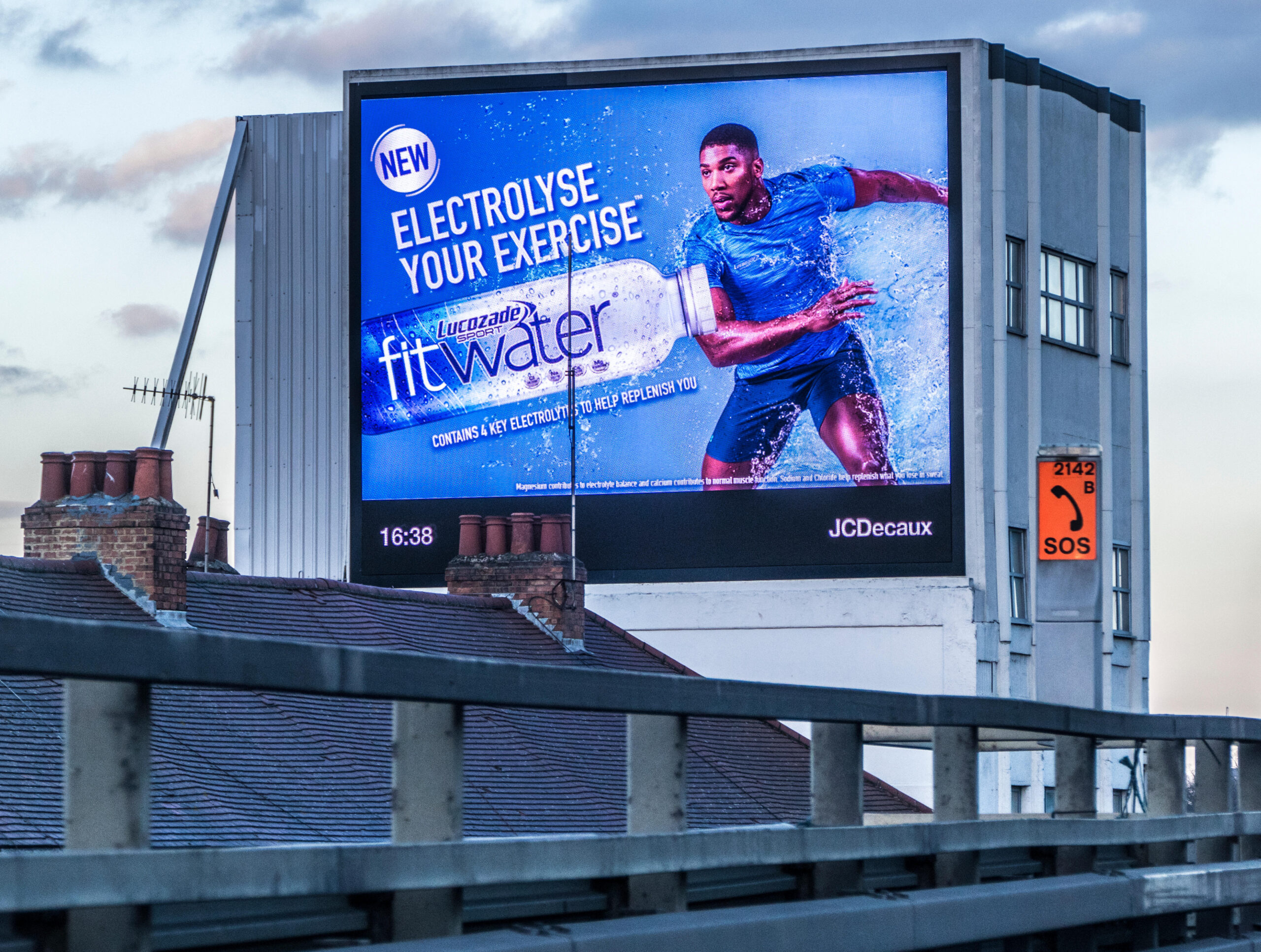 Lucozade digital billboard sportsman advert on the side of a historic 1954 concrete building, next to the M4 motorway, Brentford, London, England, UK.