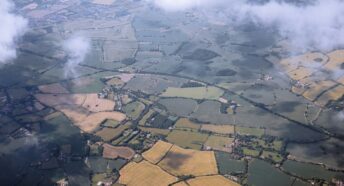 An aerial view of a field with clouds in the sky