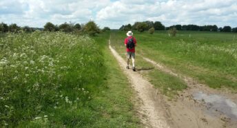 attractive green landscape with man walking along footpath